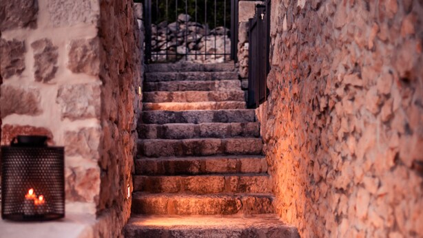 Eine Steintreppe führt zu einem von einer Mauer umgebenen Eingangstor.