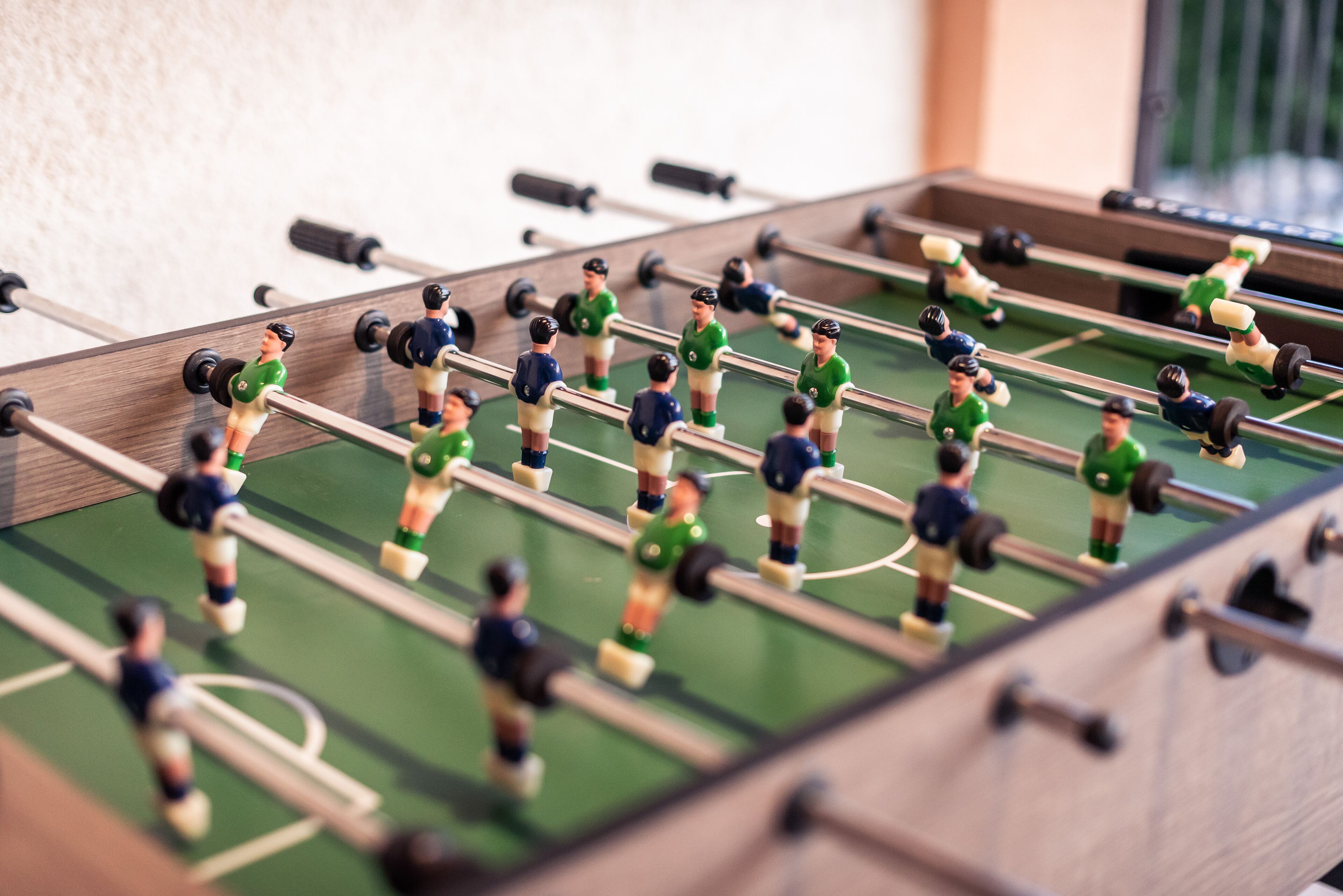 Een tafelvoetbaltafel met spelers in groene en blauwe tenues.