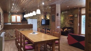 Ein gemütlicher Essbereich mit Holztisch und -stühlen, einer Steinwand und einem an der Wand befestigten Fernseher.