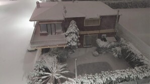 Ein zweistöckiges Gebäude mit verschneitem Dach und einem sichtbaren Balkon.