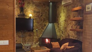 Ein gemütliches Zimmer mit Steinwand, Kamin, Fernseher und einer Couch.