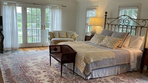 Un dormitorio con una cama grande, un banco de madera y una alfombra estampada.