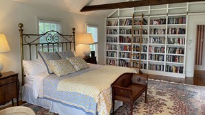 Un dormitorio con una cama grande, una estantería de madera y una escalera.