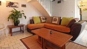 A cozy living room with a sectional sofa, a wooden coffee table, a potted plant, and a staircase leading to another level. - Independent house with garden at equestrian, pets allowed (Montabard)