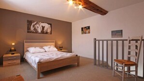 A bedroom with a wooden bed, two bedside tables with lamps, a chair, and horse-themed wall art. - Independent house with garden at equestrian, pets allowed (Montabard)