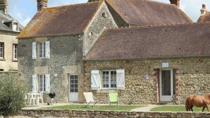 A stone building with a sloped roof, white shutters, and a small garden with outdoor furniture. - Independent house with garden at equestrian, pets allowed (Montabard)