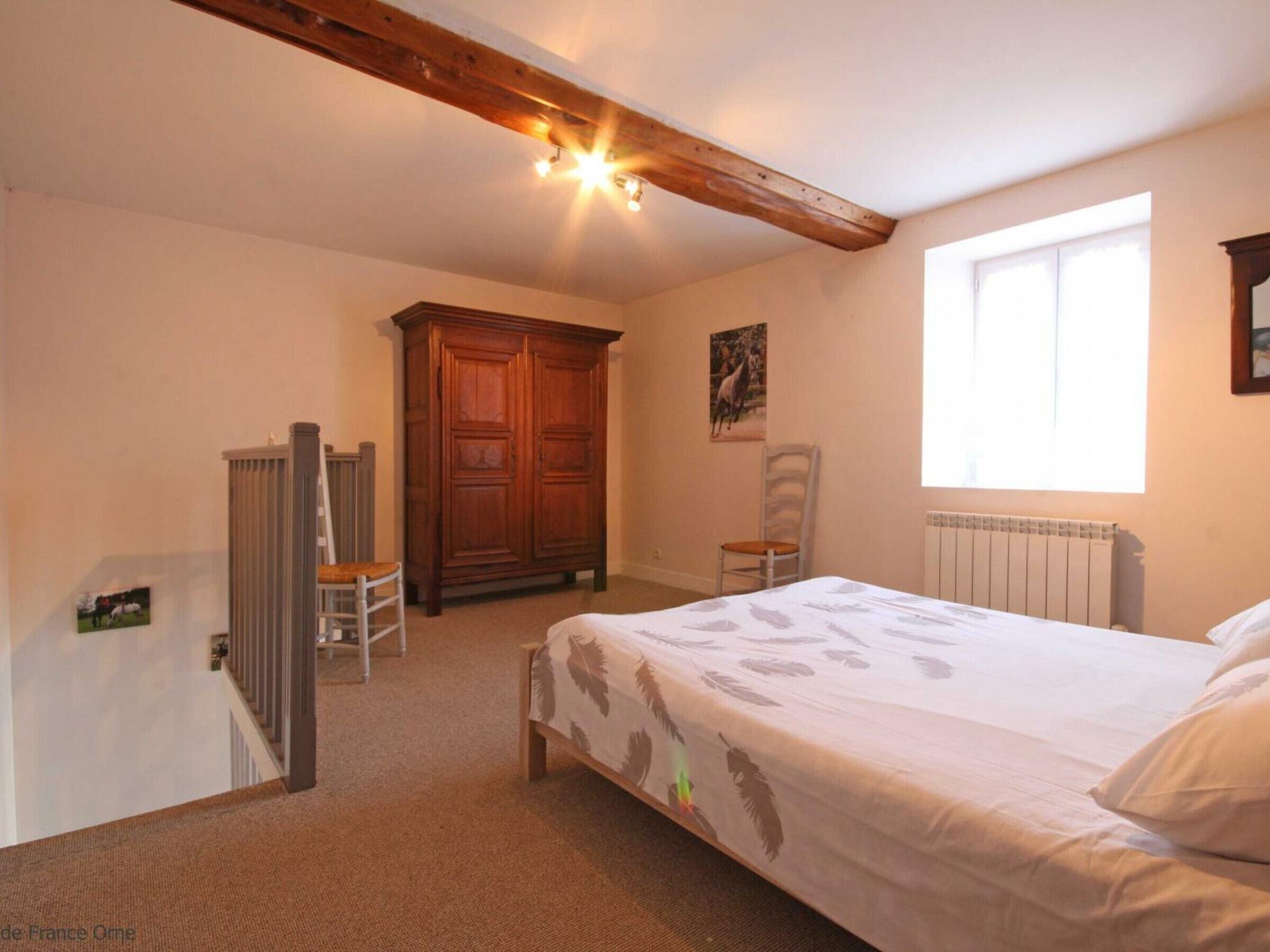 A bedroom with a bed, a wooden wardrobe, a radiator, and a window.