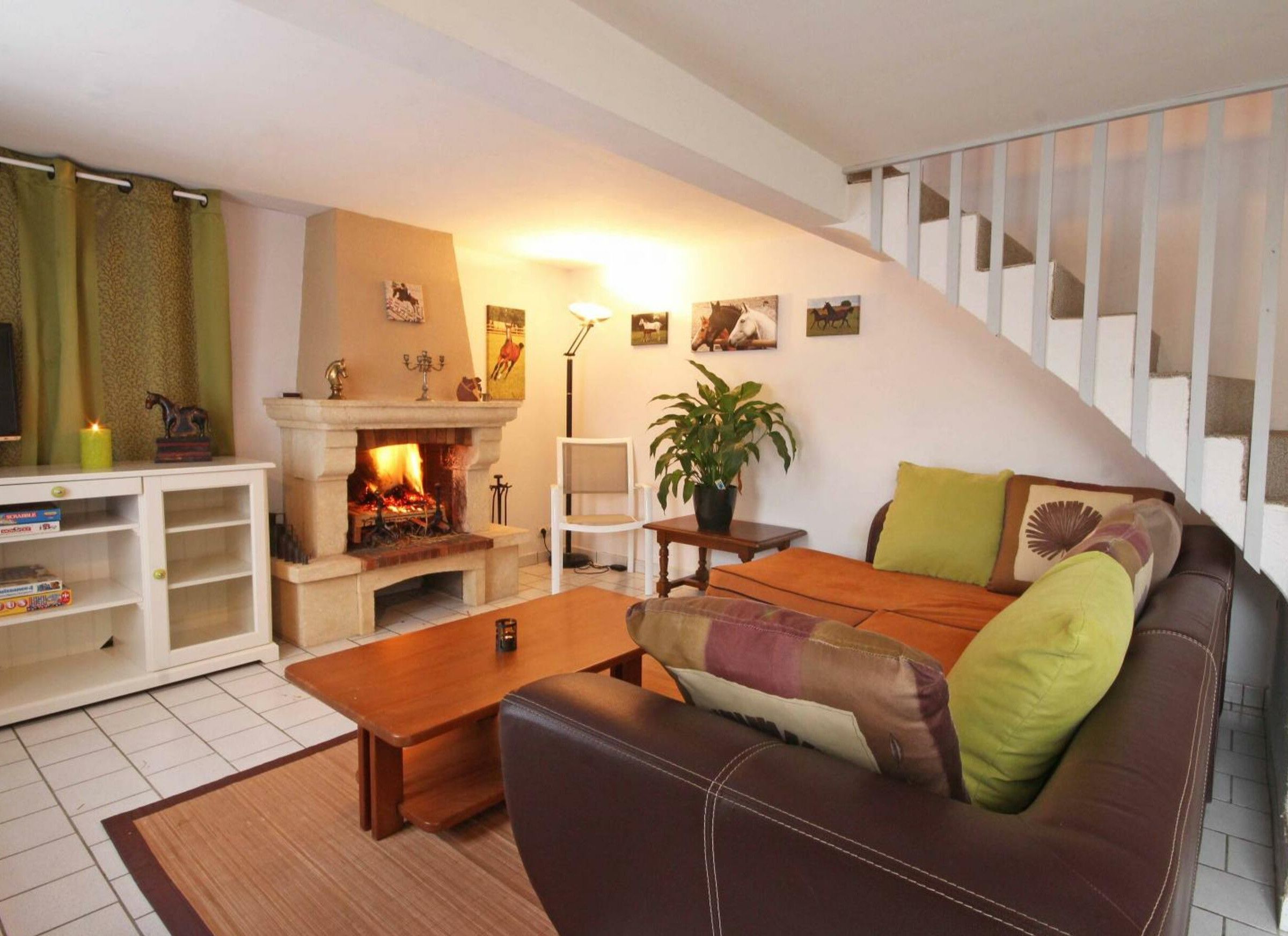 Een gezellige woonkamer met een open haard, een bank, een bijzettafeltje en een trap.