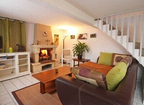 A cozy living room with a fireplace, a sofa, a coffee table, and a staircase.