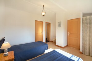 A bedroom with two beds, a nightstand with a lamp, and a ceiling light fixture. - OULIVADE Luberon in Provence. 4 kms from ROUSSILLON Villa for 5 people (Vaucluse)
