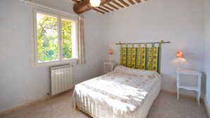Un dormitorio con una cama, dos lámparas de noche, un ventanal y un radiador.