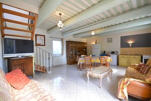 A spacious living area with a sofa, a dining table, and a kitchen in the background. - OULIVADE Luberon in Provence. 4 kms from ROUSSILLON Villa for 5 people (Vaucluse)