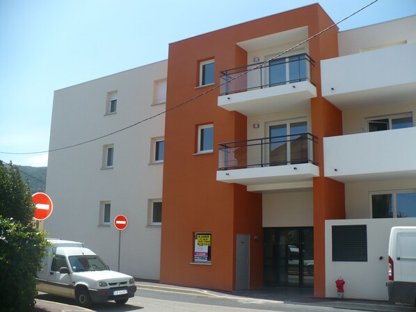 A multi-story building with balconies and a sign indicating a lower floor.