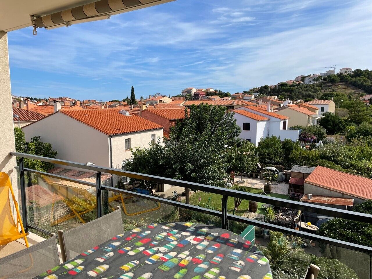 A balcony with a view of a residential area, featuring houses with red-tiled roofs and greenery.