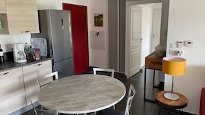 A modern kitchen with a round dining table, a refrigerator, and a coffee maker.