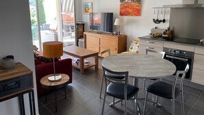 A modern kitchen with a dining area, a TV, and a painting on the wall.