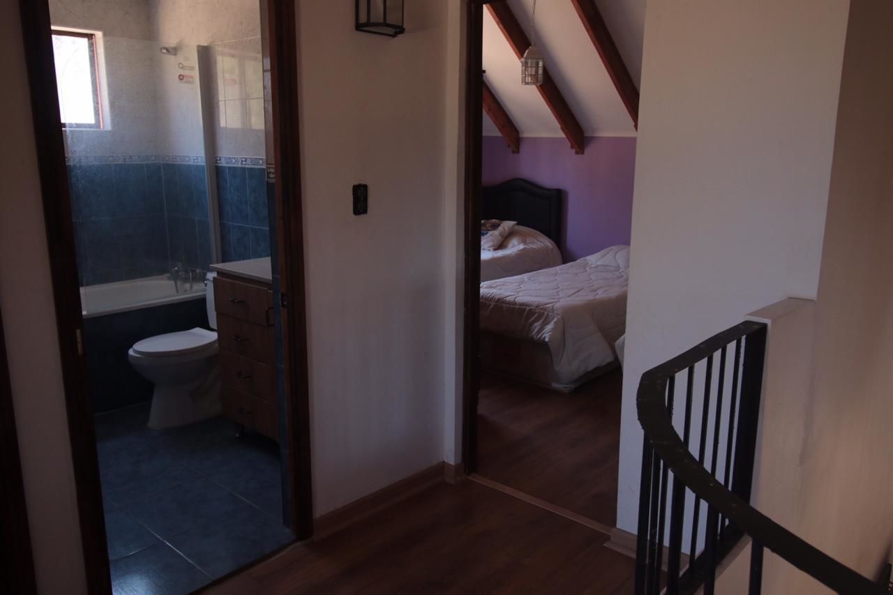 Un pasillo estrecho que conduce a un dormitorio con cama y un baño con inodoro y lavamanos.