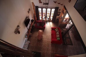 A spacious living room with a red sofa, a wooden coffee table, and a chandelier. - Casa en Parcela (Zapallar)