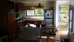 Une cuisine de taille réduite avec des meubles en bois, une table à manger avec des chaises, un réfrigérateur et une fenêtre donnant sur l’extérieur.