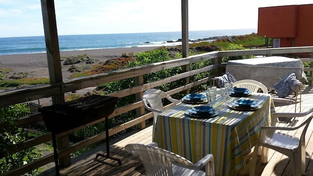 Un espace extérieur aménagé pour prendre les repas, avec vue sur la plage et l’océan.