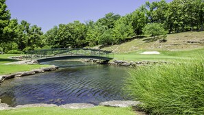 A bridge over a pond with a golf course in the background. - Stonebridge Condo and Golf Resort (Branson West)