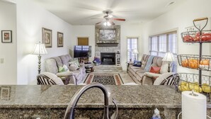 A spacious living room with a fireplace, comfortable seating, and a kitchen area with granite countertops. - Stonebridge Condo and Golf Resort (Branson West)