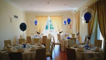 A banquet hall with round tables set for dining, featuring blue and white tablecloths and balloons.