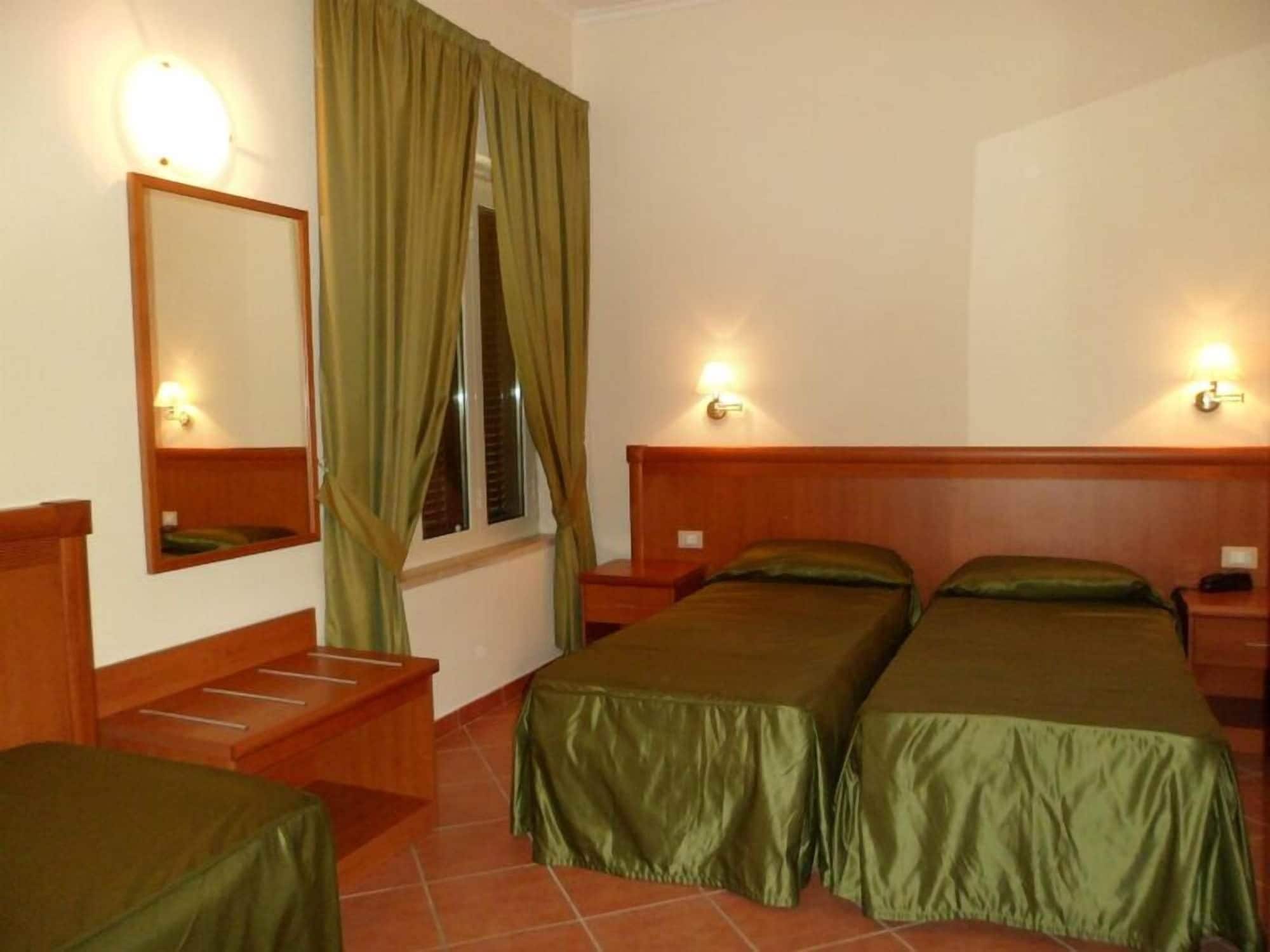 Ein Hotelzimmer mit zwei Einzelbetten, einem Holzkopfende, einem Nachttisch, einem Spiegel, einem Fenster mit Vorhängen und Wandleuchten.