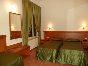 A hotel room with two single beds, a wooden headboard, a nightstand, a mirror, a window with curtains, and wall-mounted lights. - Villamaria Park Hotel (Albano Laziale)