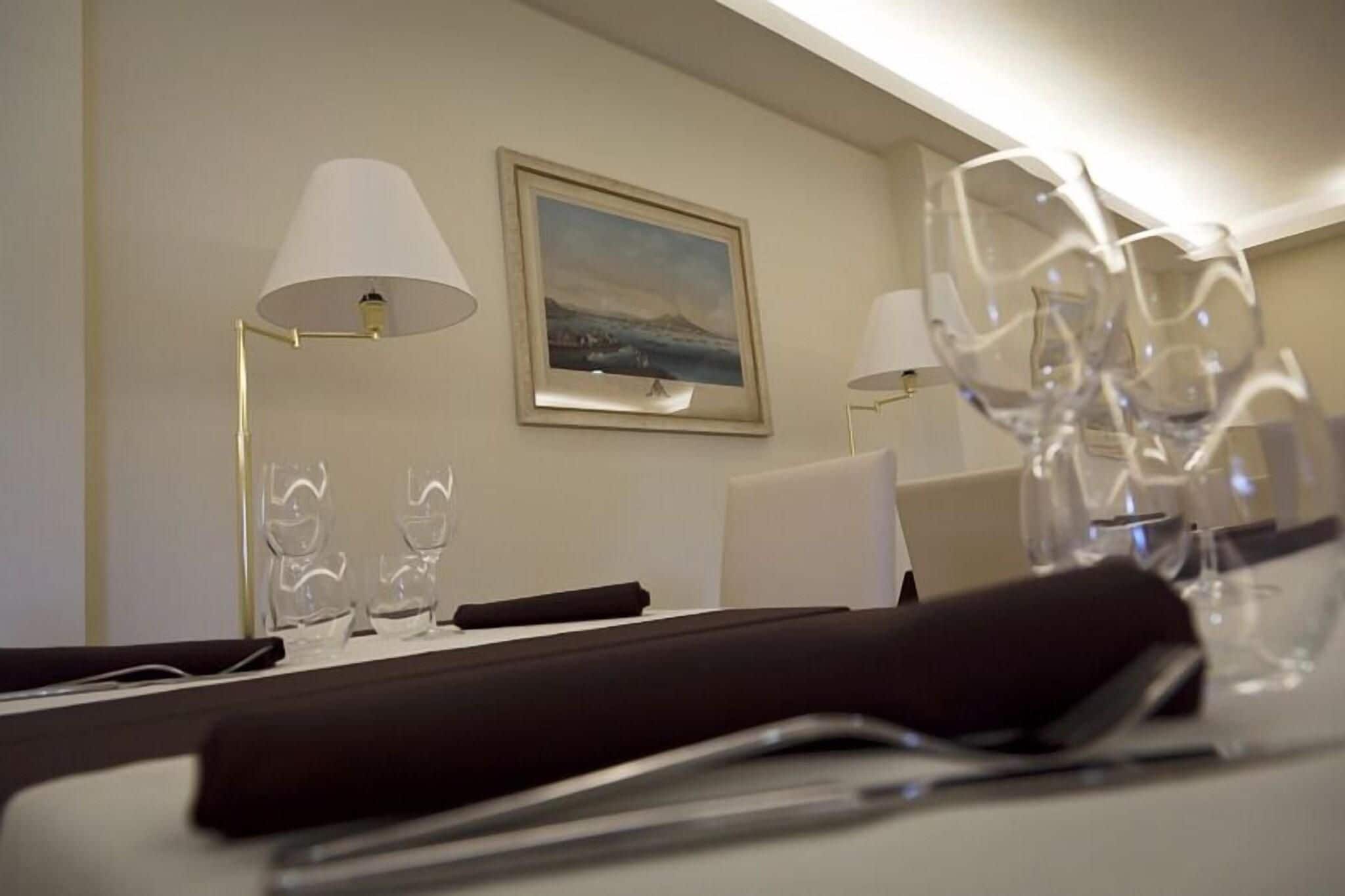 Een hotelkamer met een netjes gedekte eettafel, twee lampen en een ingelijst schilderij aan de muur.