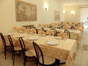 Un comedor con mesas dispuestas para una comida, con sillas y manteles.