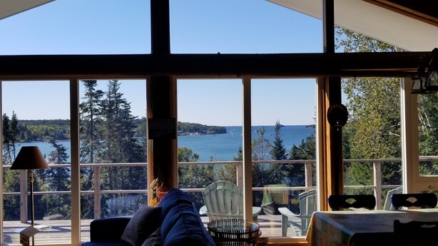 A room with large windows overlooking a lake, a fan, and a lamp. - Relaxing ocean front property with picturesque harbor views (Addison)