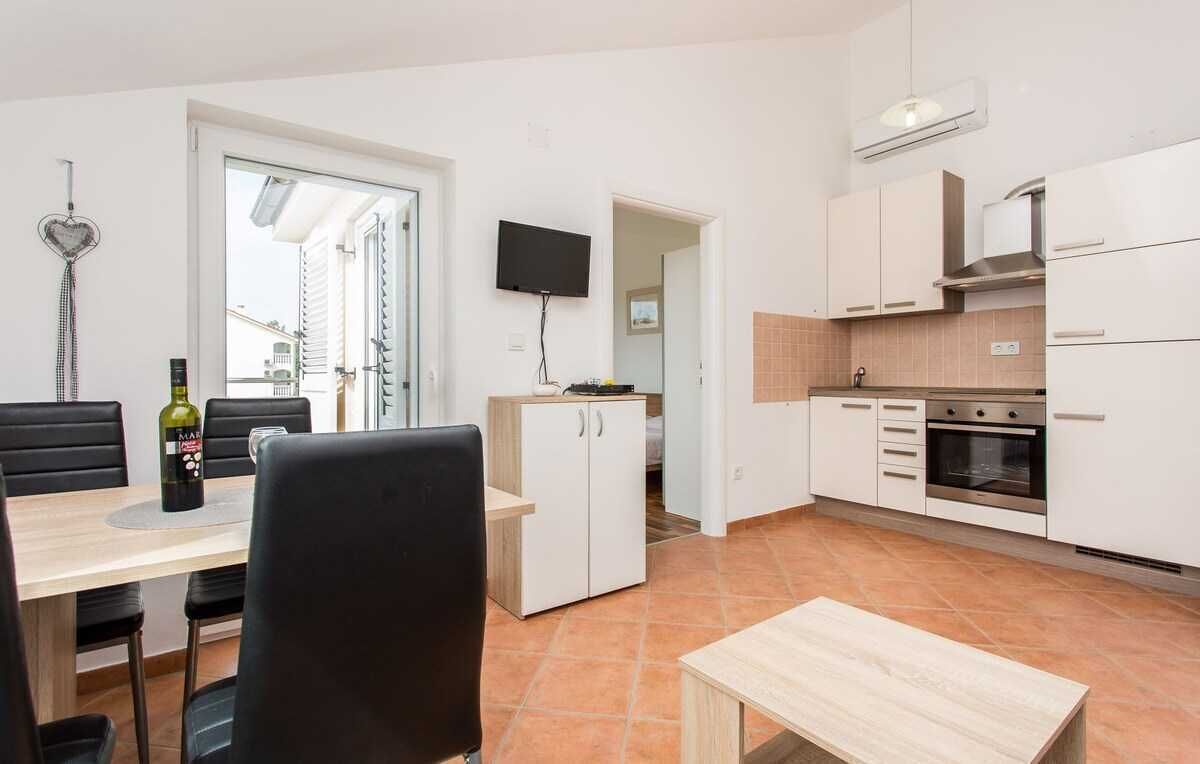 A modern kitchen with white cabinets, a built-in oven, and a flat-screen TV.