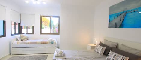 Une chambre moderne avec un grand lit, un canapé-lit, une petite table et un tableau au mur.