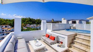 Terraza en la azotea con sofá, mesa y jacuzzi.