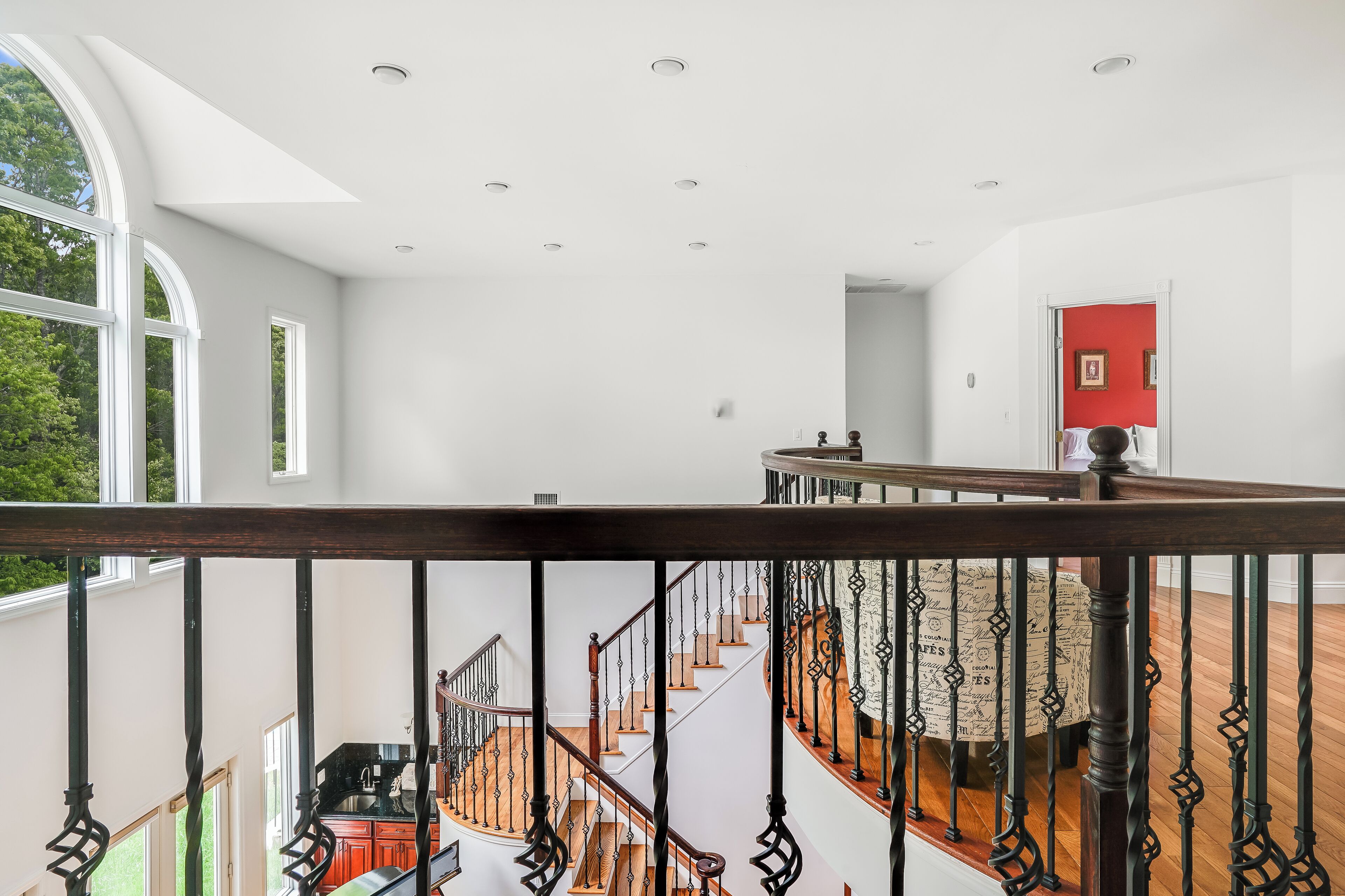 A spacious interior with a wooden staircase, white walls, and a red accent wall.
