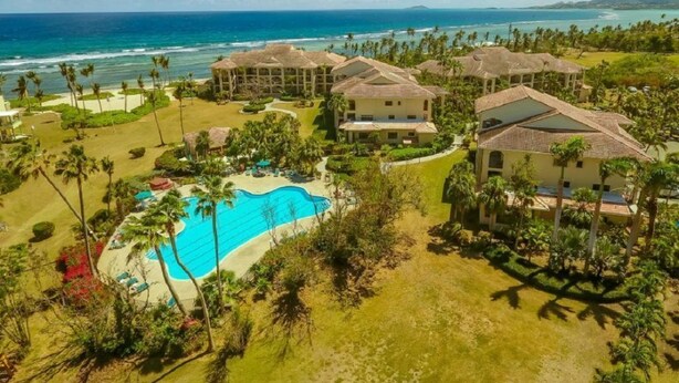 Un resort con diversi edifici, una piscina e vista sull'oceano.
