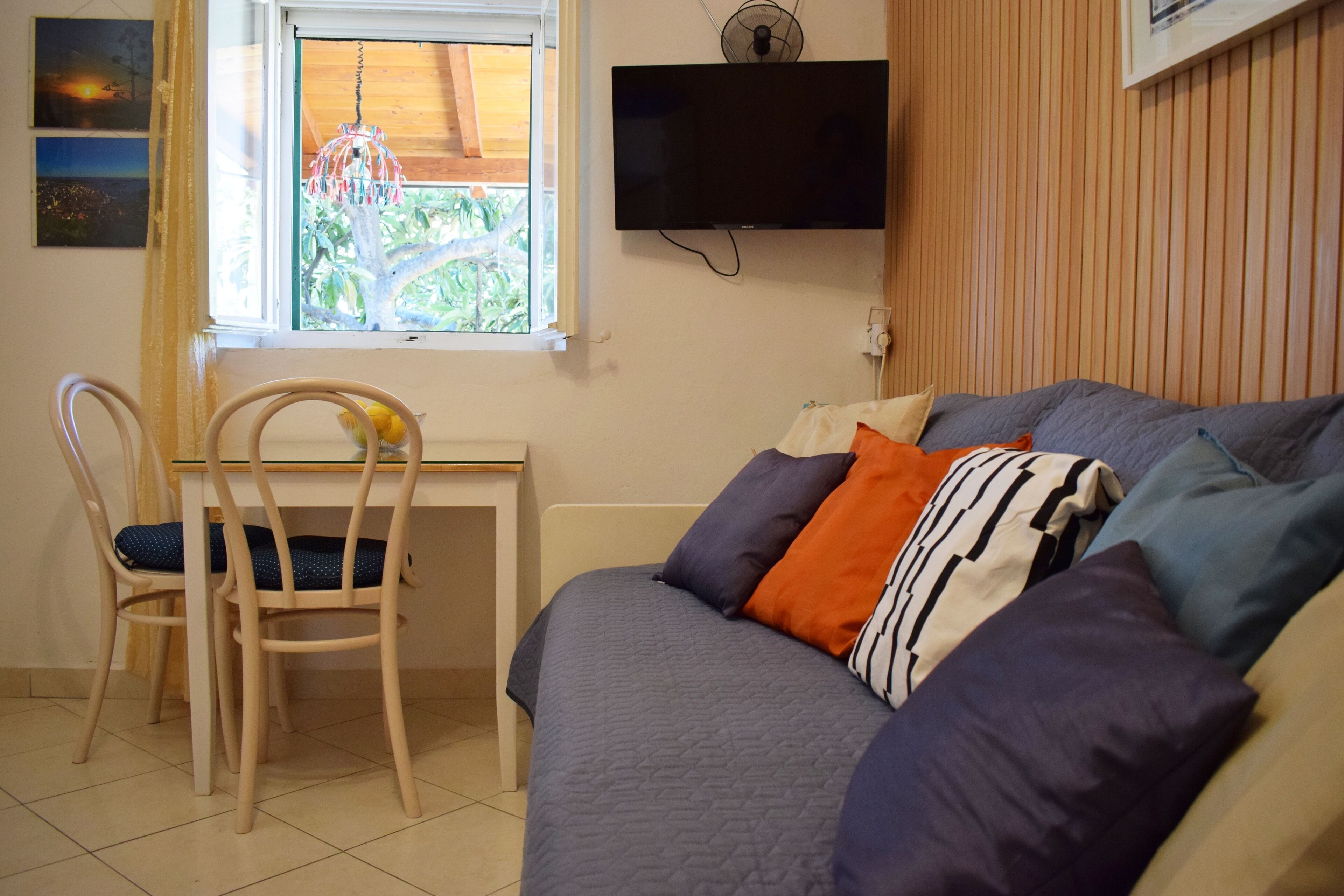 Een slaapkamer met een bed, een bureau en een stoel. Er is een raam met uitzicht op groen.