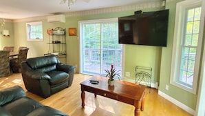 A living room with a sectional sofa, a leather armchair, a wooden coffee table, and a ceiling fan. - Lake House Private Waterfront - Lake & Beach life in Winnipesaukee (Laconia)
