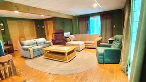 A living room with a wooden floor, a round rug, a sofa, a chair, and a coffee table. - Lake House Private Waterfront - Lake & Beach life in Winnipesaukee (Laconia)