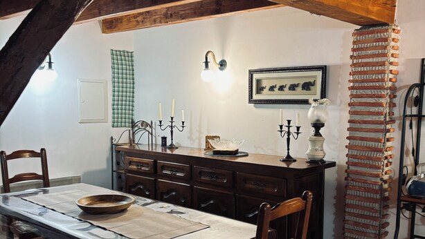 Un espace repas comprenant une table en bois, des chaises et un sol carrelé.