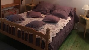 Une chambre confortable avec un lit en bois, une table de chevet, une lampe et un panneau mural sur lequel on peut lire le mot « NATURE ».