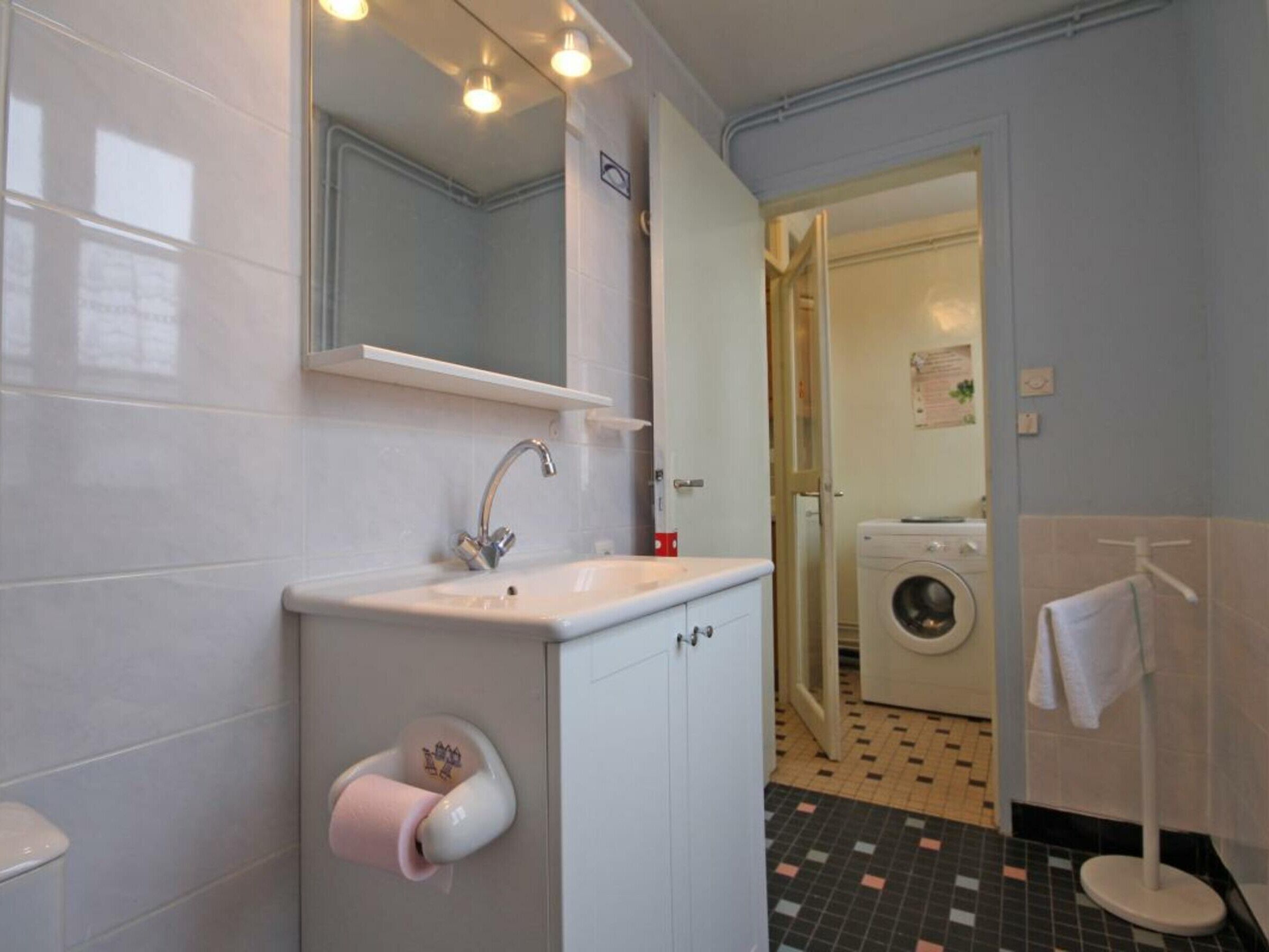 Une salle de bain équipée d’un lavabo, d’un miroir, de toilettes et d’un lave-linge.