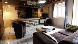 Un salon chaleureux avec une cheminée en pierre, un téléviseur et un canapé.