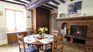Un coin repas agrémenté d’une cheminée en briques, de chaises en bois et d’une table dressée pour quatre personnes.