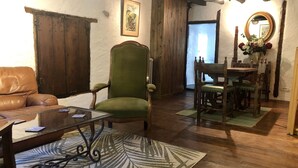 Un accogliente soggiorno con un divano in pelle, una poltrona verde, un tavolino in vetro e un tappeto decorato.