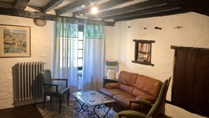 Un soggiorno accogliente con un divano in pelle marrone, un tavolino in vetro, un termosifone, un quadro incorniciato e una libreria.