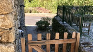 Un muro in pietra con un cancello in legno e una recinzione metallica.