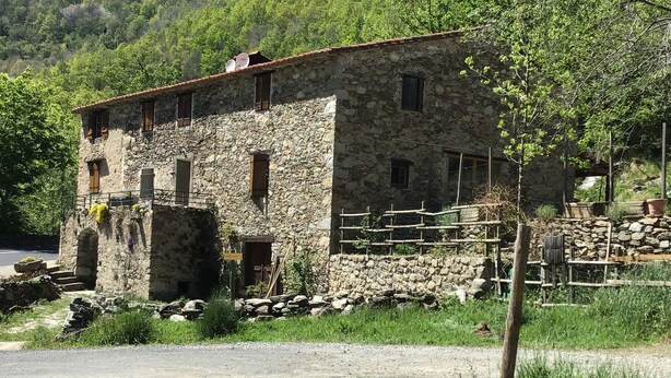 Un edificio rustico in pietra con numerose finestre e una recinzione in legno.