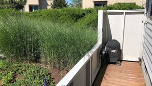 Une terrasse en bois avec une clôture blanche, un drapeau américain et un objet noir sur la droite.